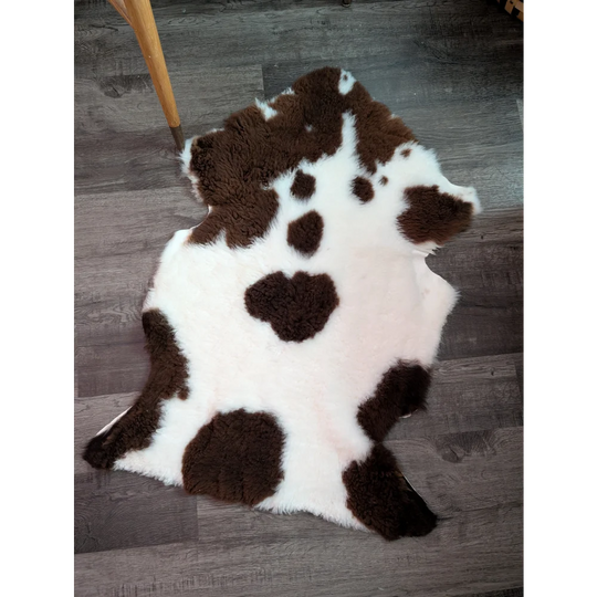 A plush white and brown highland spotted grade a- sheepskin rug with a soft fluffy texture perfect for cozy decor