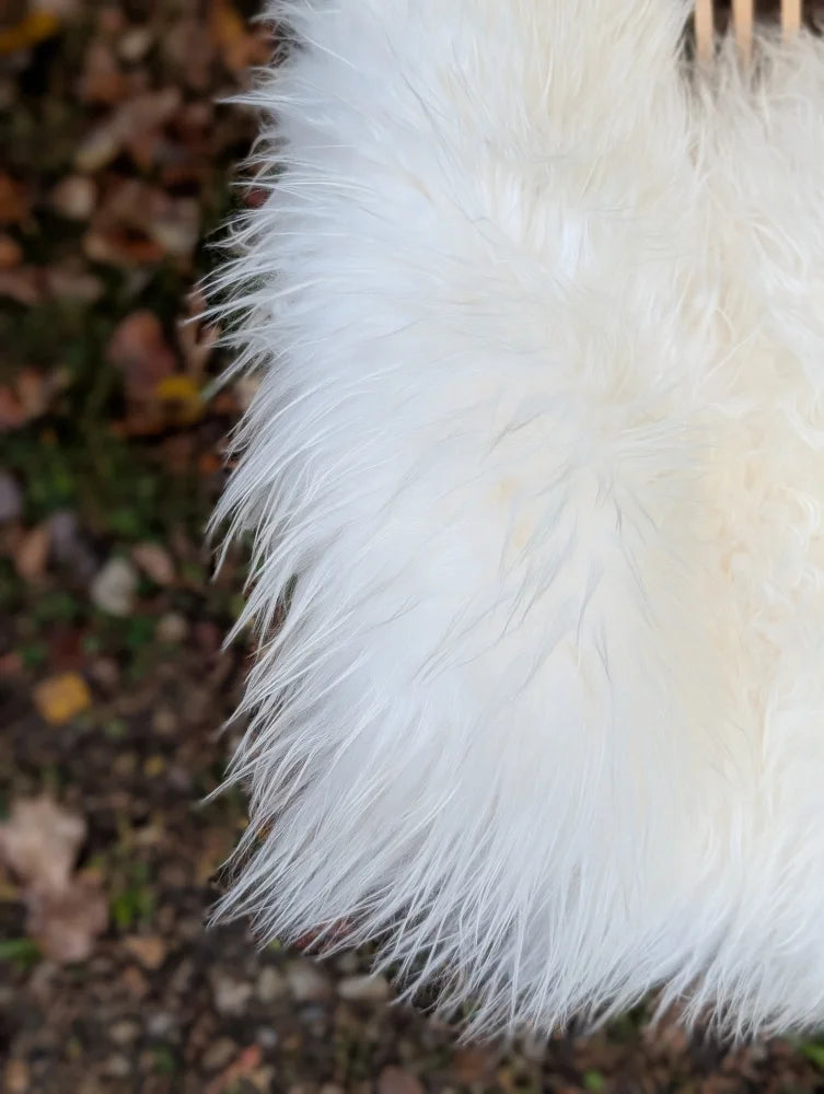 A plush natural white icelandic sheepskin pom-pom accessory with large long wool texture