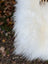 A plush natural white icelandic sheepskin pom-pom accessory with large long wool texture