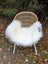 Large long wool natural white icelandic sheepskin throw draped over woven wicker chair with white metal legs