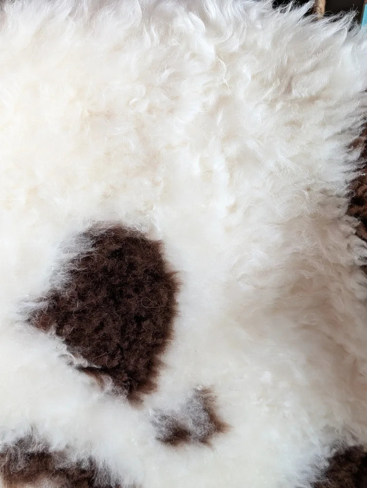 White and brown curly fluffy tibet highland spotted grade a- sheepskin rug with textured surface