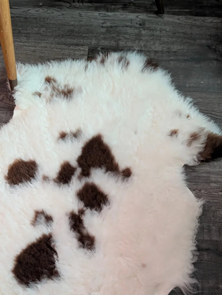 A fluffy white and brown spotted tibet highland spotted grade a- sheepskin rug with a soft natural texture
