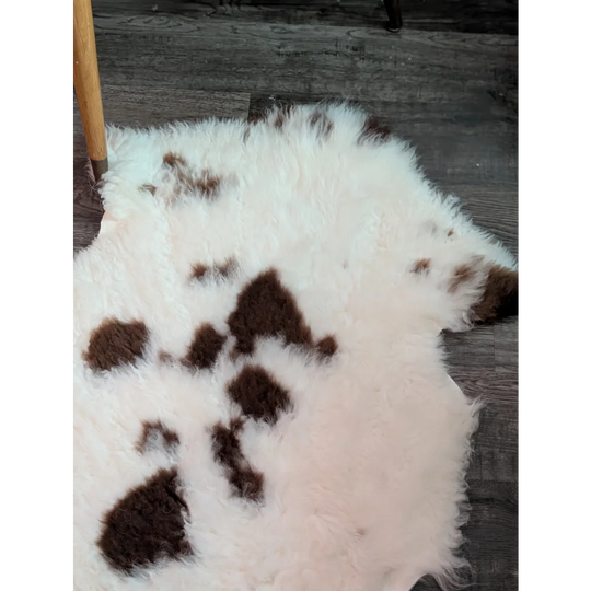 A fluffy white and brown spotted tibet highland spotted grade a- sheepskin rug with a soft natural texture