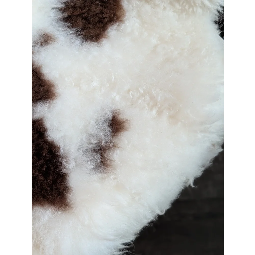 A plush fluffy white and brown tibet highland spotted grade a- sheepskin rug with a soft curly texture