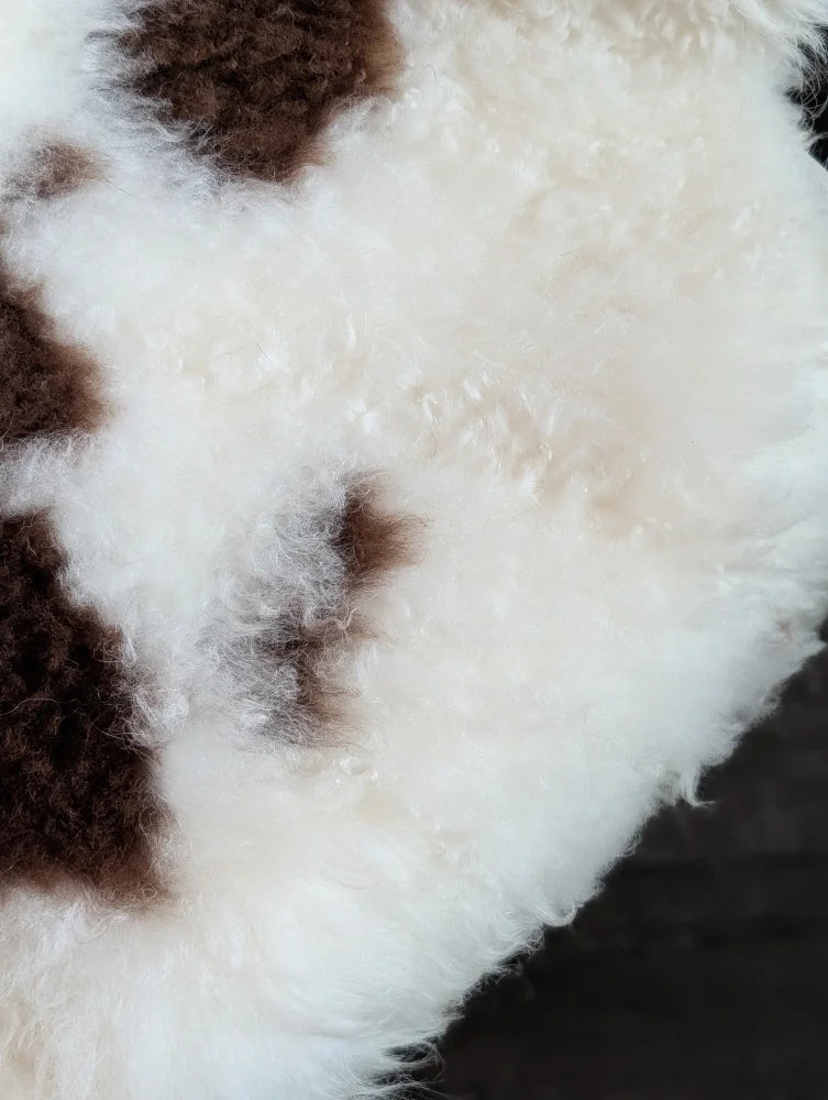 A plush fluffy white and brown tibet highland spotted grade a- sheepskin rug with a soft curly texture