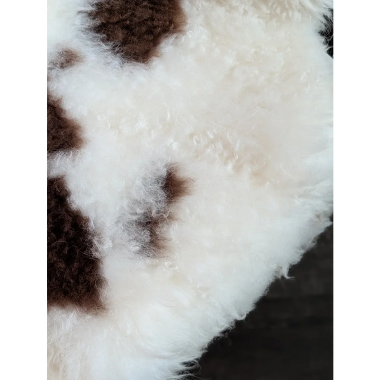 A plush fluffy white and brown tibet highland spotted grade a- sheepskin rug with a soft curly texture