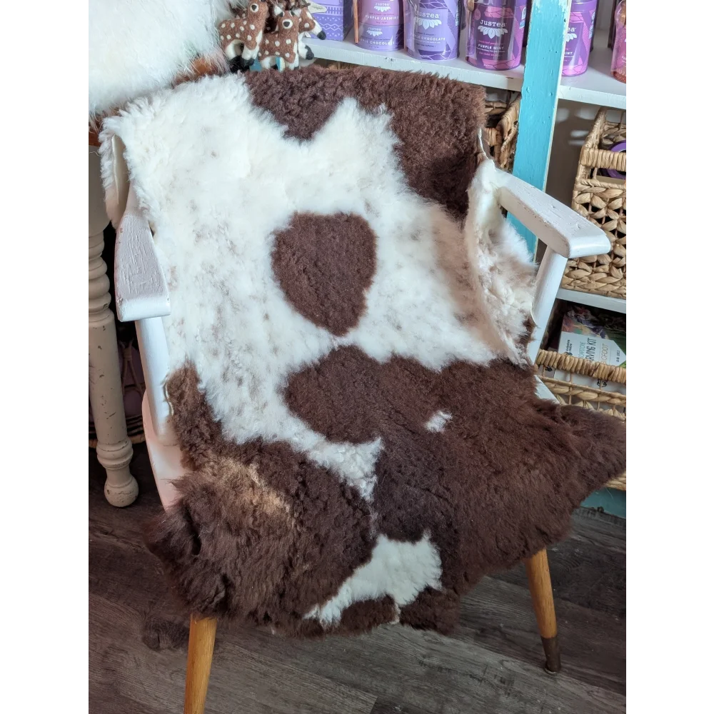 Brown and white highland spotted grade b sheepskin rug draped over a chair showcasing soft sheepskin rugs