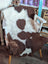 Brown and white highland spotted grade b sheepskin rug draped over a chair showcasing soft sheepskin rugs