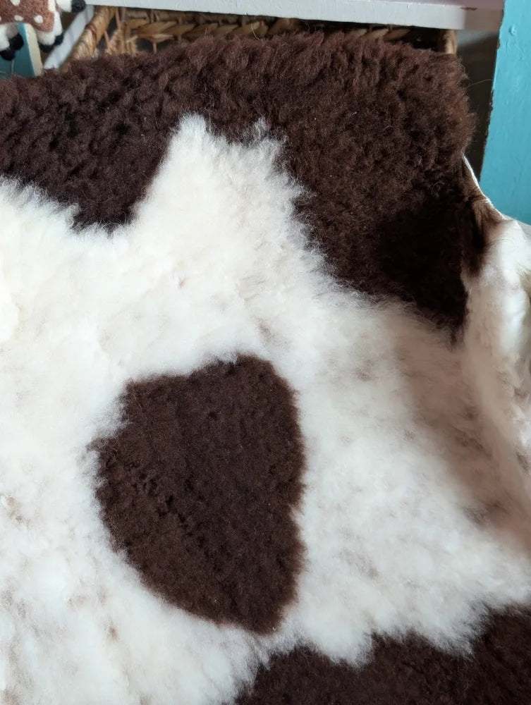 A plush grade b sheepskins rug with a soft white base and rich brown patches in highland spotted style