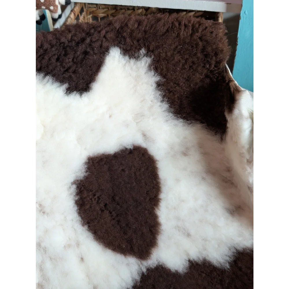 A plush grade b sheepskins rug with a soft white base and rich brown patches in highland spotted style
