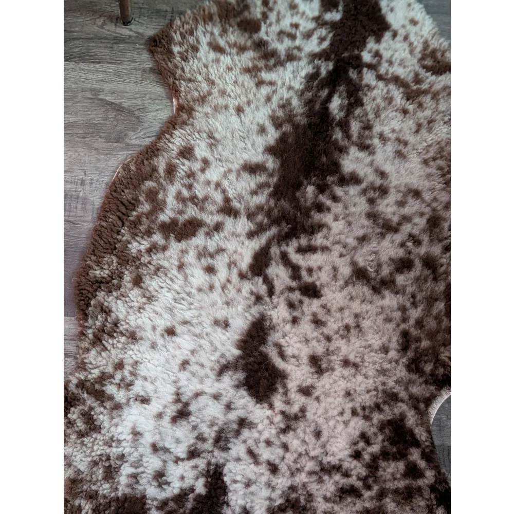 A plush grade b sheepskin rug with highland spotted white and brown soft irregular pattern perfect for cozy spaces