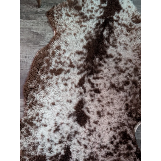 A plush grade b sheepskin rug with highland spotted white and brown soft irregular pattern perfect for cozy spaces