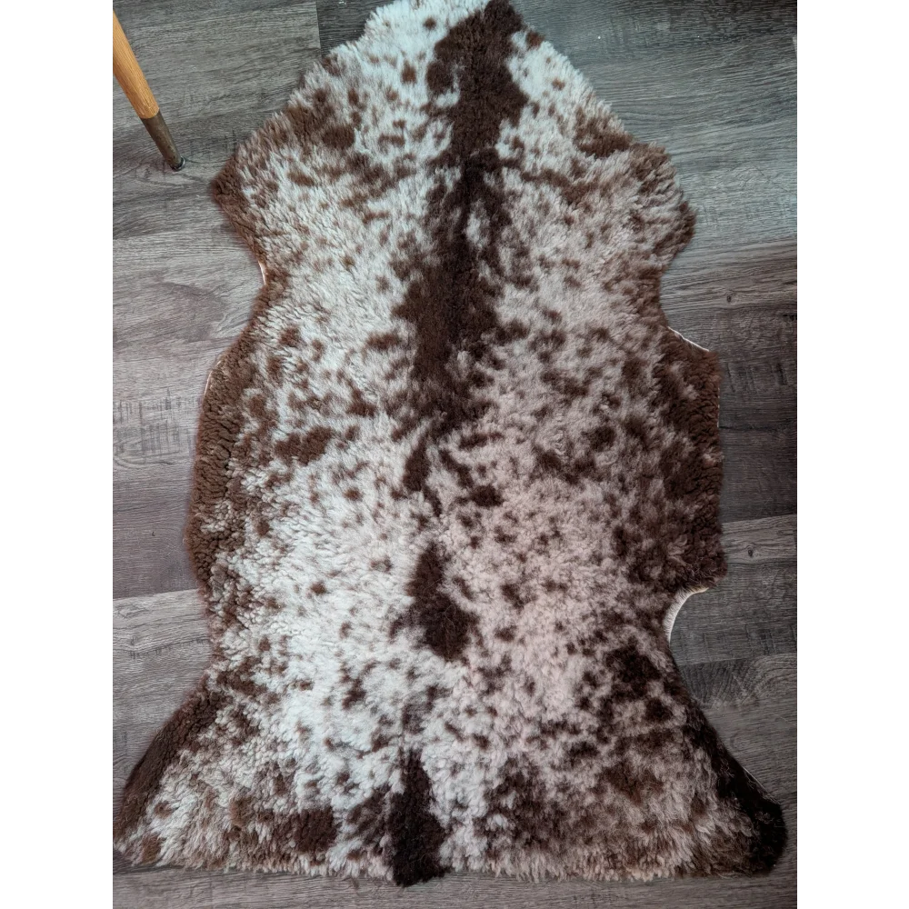 A plush irregular brown and white highland spotted grade b sheepskin rug with a soft fluffy texture