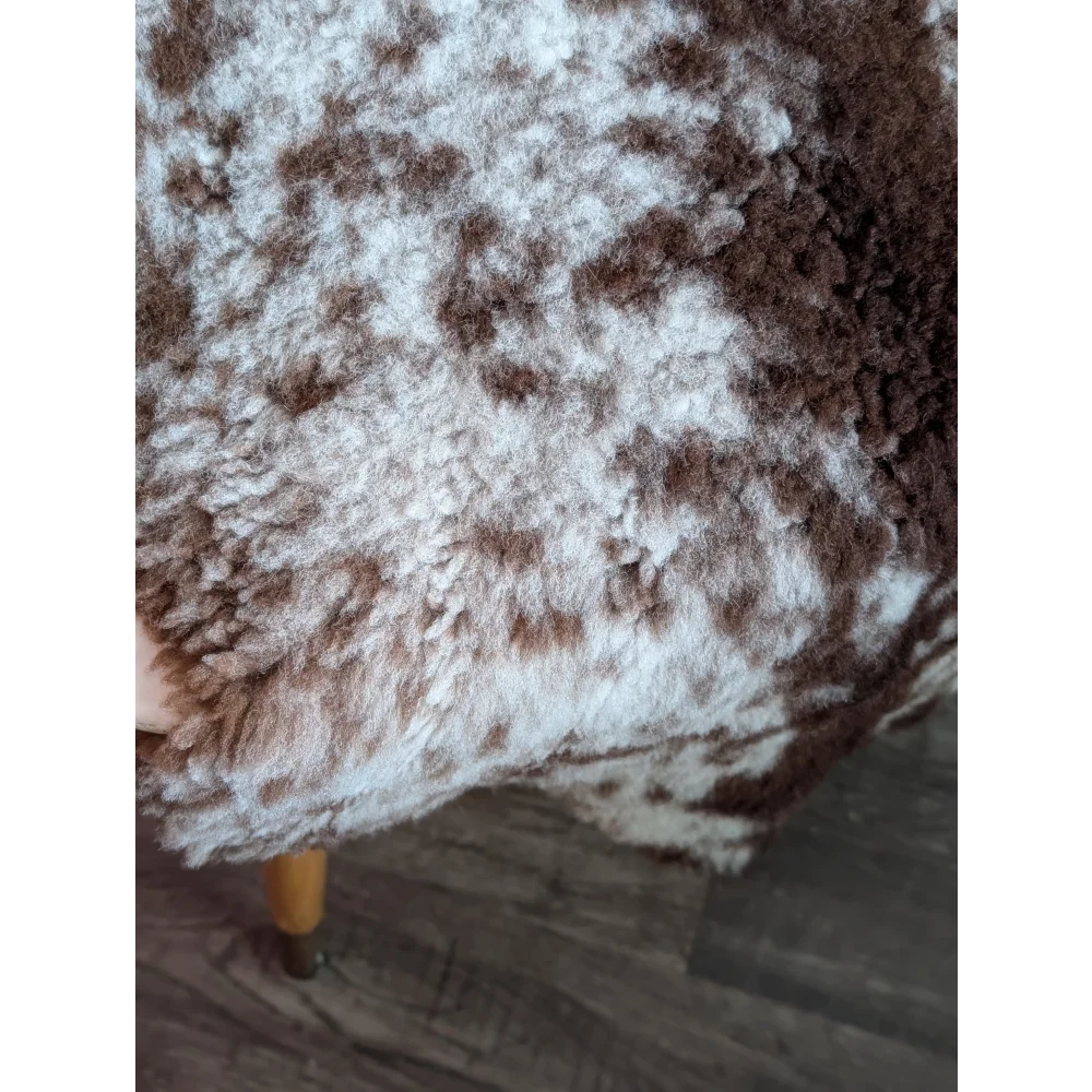 A plush brown and white highland spotted grade b sheepskin throw with soft textured surface perfect for cozying up