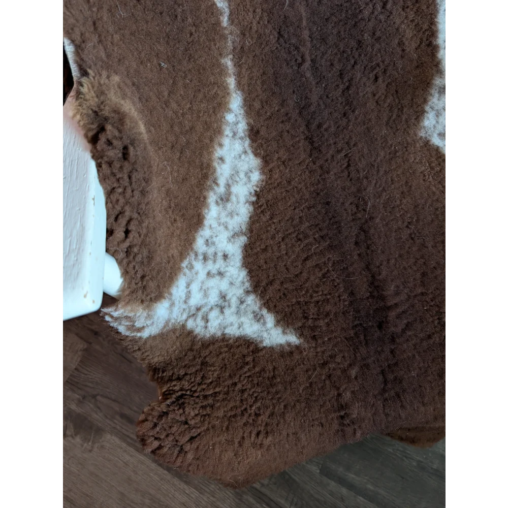 Brown and white highland spotted grade b sheepskin rug with plush textured surface for cozy home decor