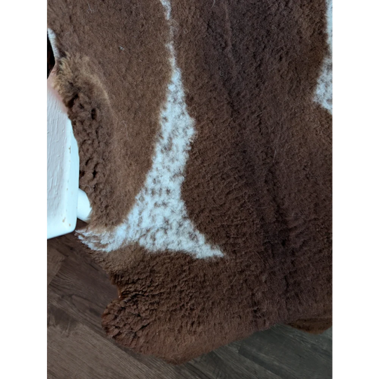 Brown and white highland spotted grade b sheepskin rug with plush textured surface for cozy home decor