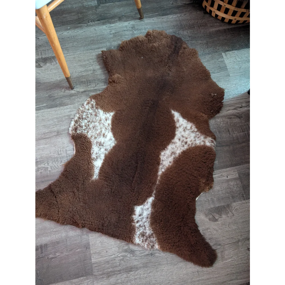 Brown and white highland spotted grade b sheepskin rug with natural irregular shape perfect for cozy decor