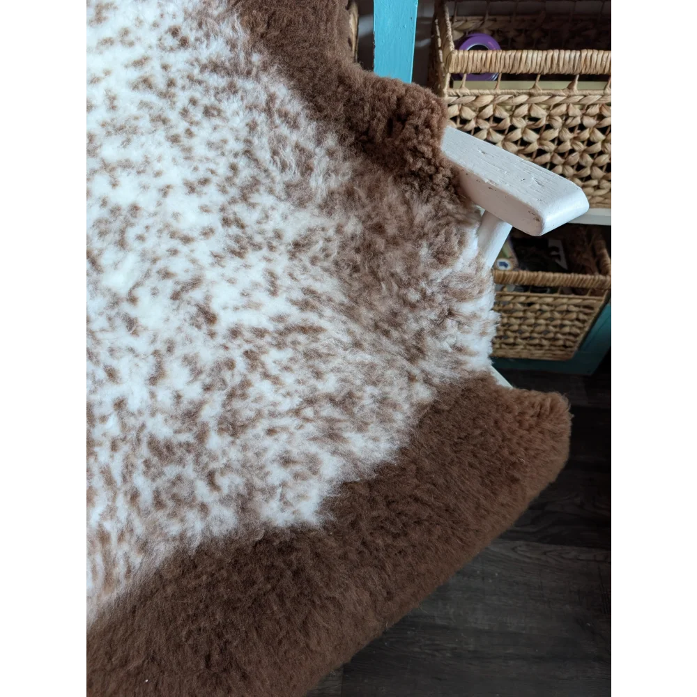 A cozy fluffy brown and white tibet highland spotted grade a- sheepskin rug with a soft textured surface