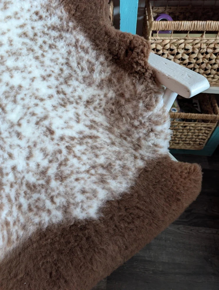 A cozy fluffy brown and white tibet highland spotted grade a- sheepskin rug with a soft textured surface