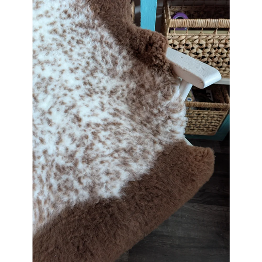 A cozy fluffy brown and white tibet highland spotted grade a- sheepskin rug with a soft textured surface
