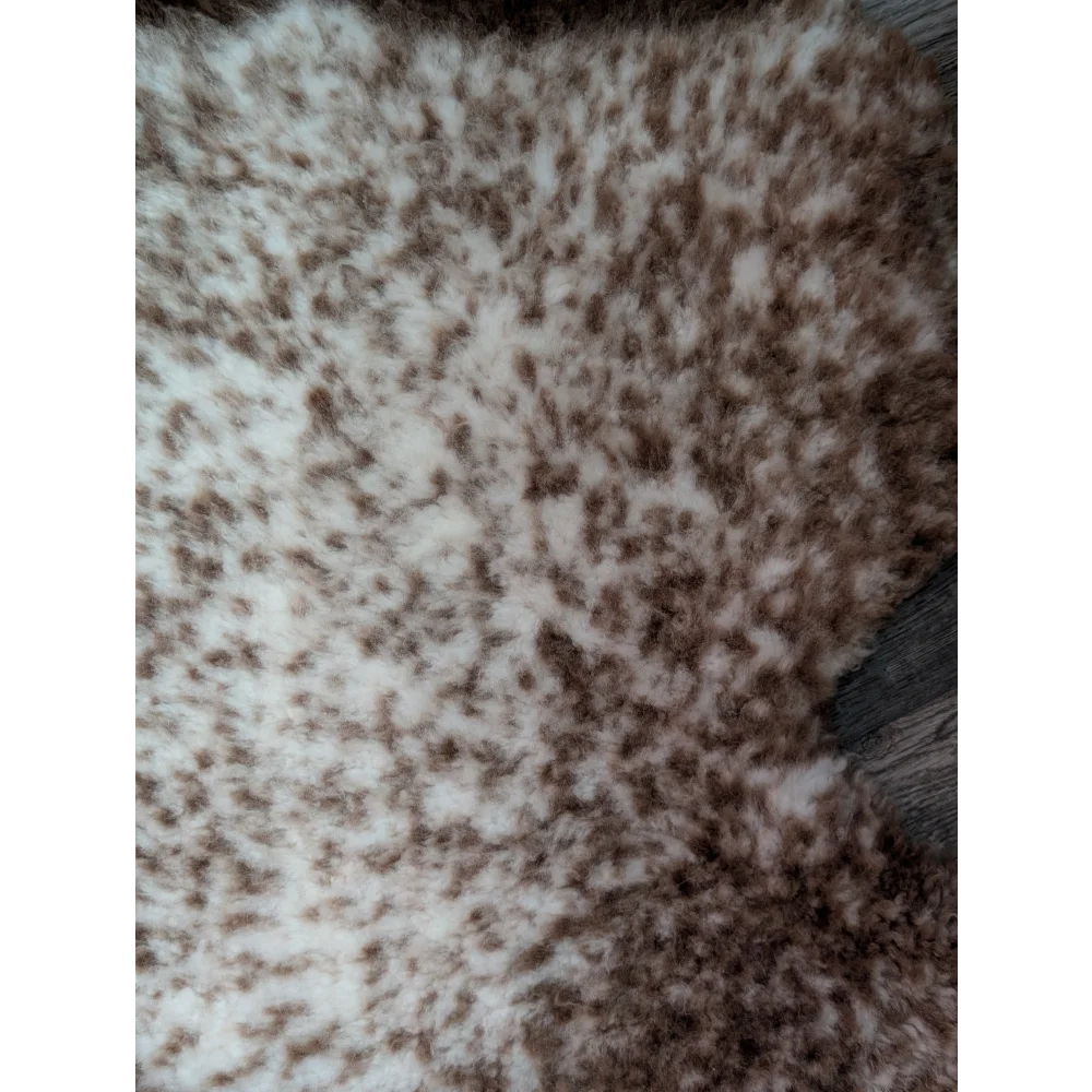 A plush cream and brown speckled faux fur throw blanket with soft texture made from grade a- tibet highland spotted sheepskins
