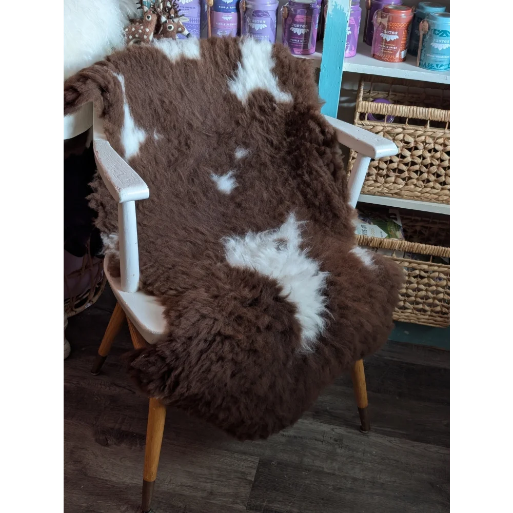 Brown and white tibet highland spotted sheepskin grade a- fur throw draped over a white wooden chair with light wood legs