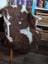 Brown and white tibet highland spotted sheepskin grade a- fur throw draped over a white wooden chair with light wood legs