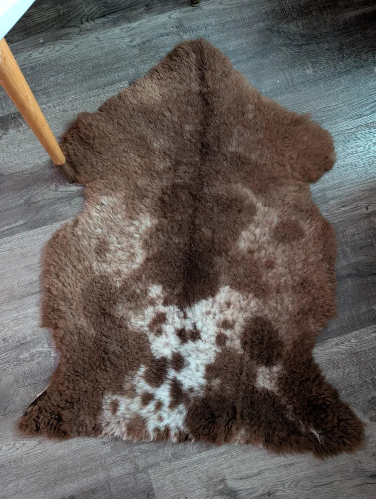 A plush natural brown and white tibet highland spotted grade a- sheepskin rug with soft fluffy texture on the floor