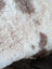 A cream highland spotted sheepskin rug with soft curly fibers and brown patches grade a tibet highland spotted