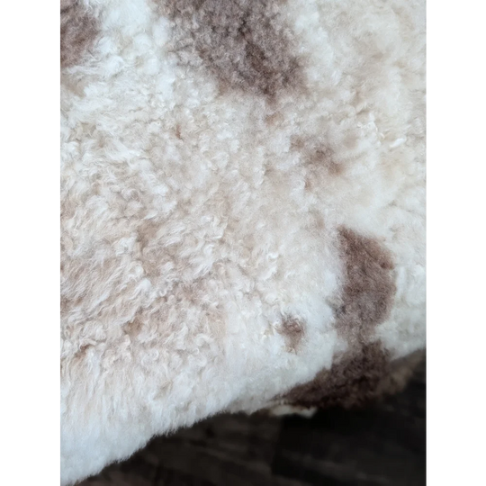 A cream highland spotted sheepskin rug with soft curly fibers and brown patches grade a tibet highland spotted