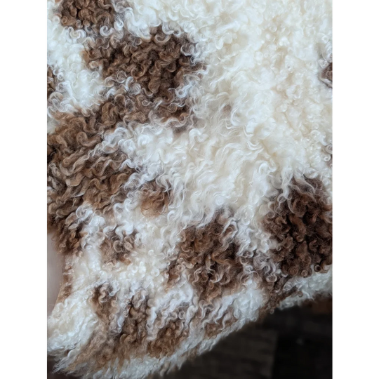 A plush cream and brown patchwork blanket made from tibet highland spotted grade a- sheepskins with curly texture