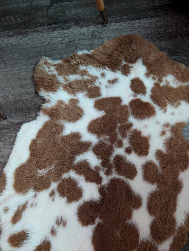 A plush grade b sheepskins highland spotted rug with natural brown and white spots in an irregular shape