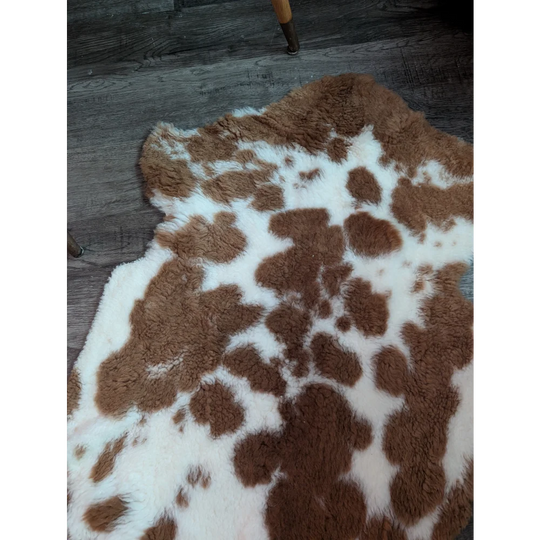 A plush grade b sheepskins highland spotted rug with natural brown and white spots in an irregular shape