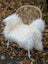 A plush natural white icelandic sheepskin long wool throw draped over a woven wicker chair with white metal legs