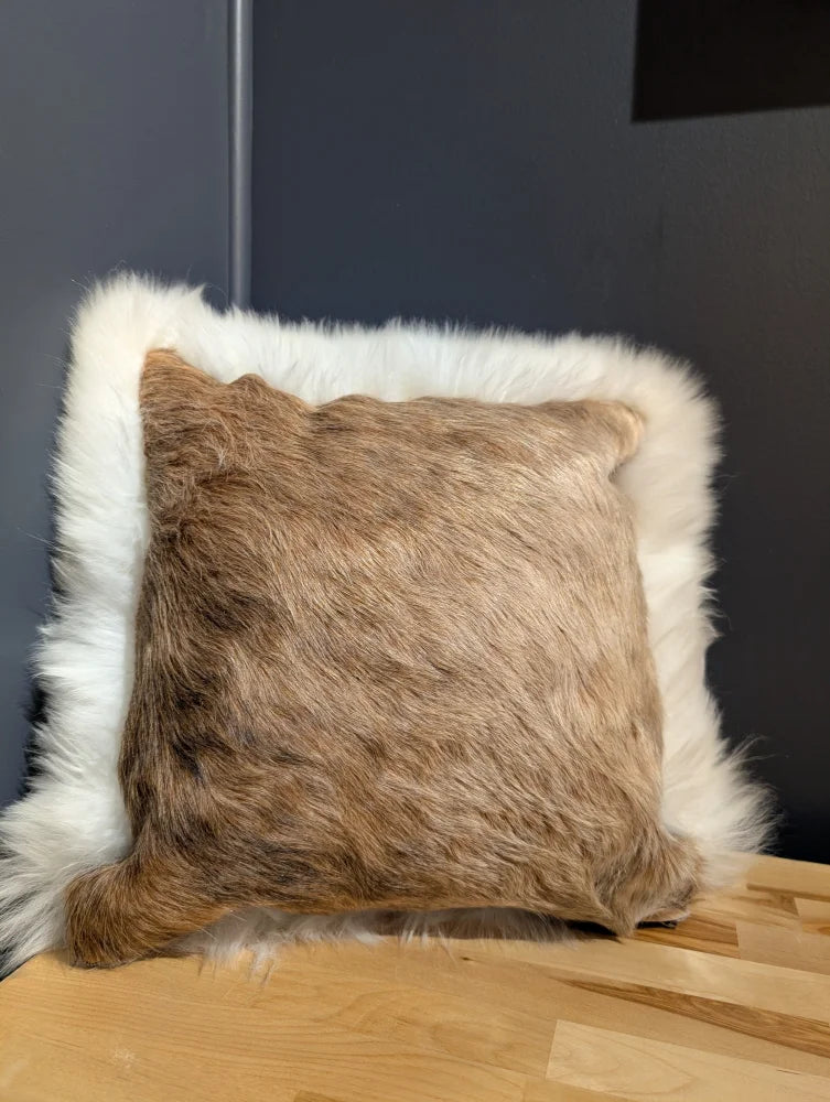 A square plush cushion in natural brown cowhide with soft white merino sheepskin trim for cozy decor