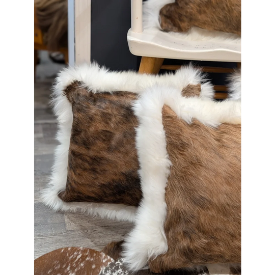 Brown and white cowhide merino sheepskin cushion with fluffy fur trim for cozy stylish home decor
