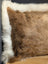 Brown faux fur pillow with white fluffy border in a unique cowhide merino sheepskin cushion design