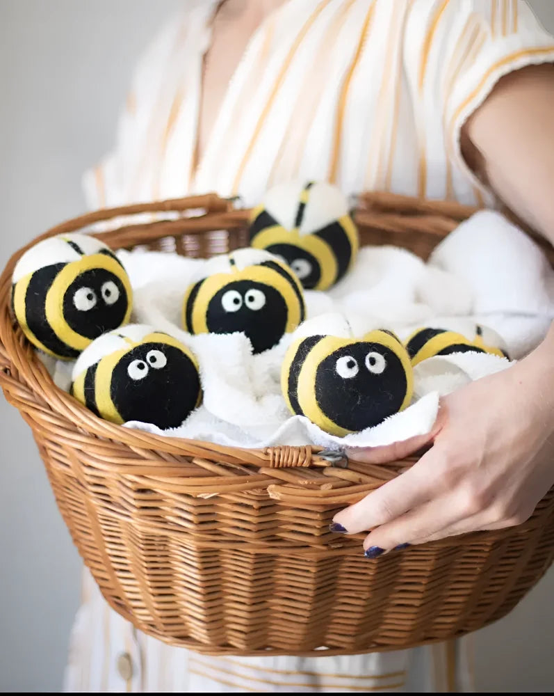 Yellow and black bee-shaped dryer balls in woven basket by Angus Oliver
