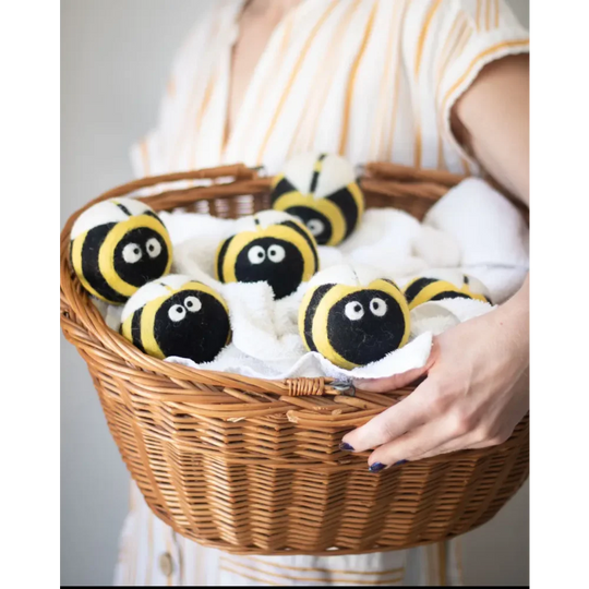Yellow and black bee-shaped dryer balls in woven basket by Angus Oliver