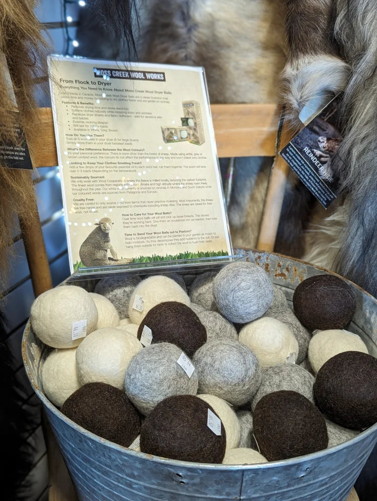 A rustic metal bucket filled with fluffy natural beige and brown wool dryer balls made from pure merino wool by moss creek wool