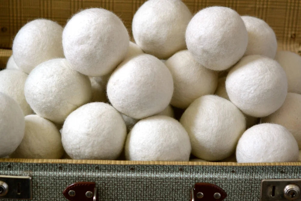 White fluffy wool dryer balls nestled in a vintage suitcase from 3 wool dryer balls wht gry brn set