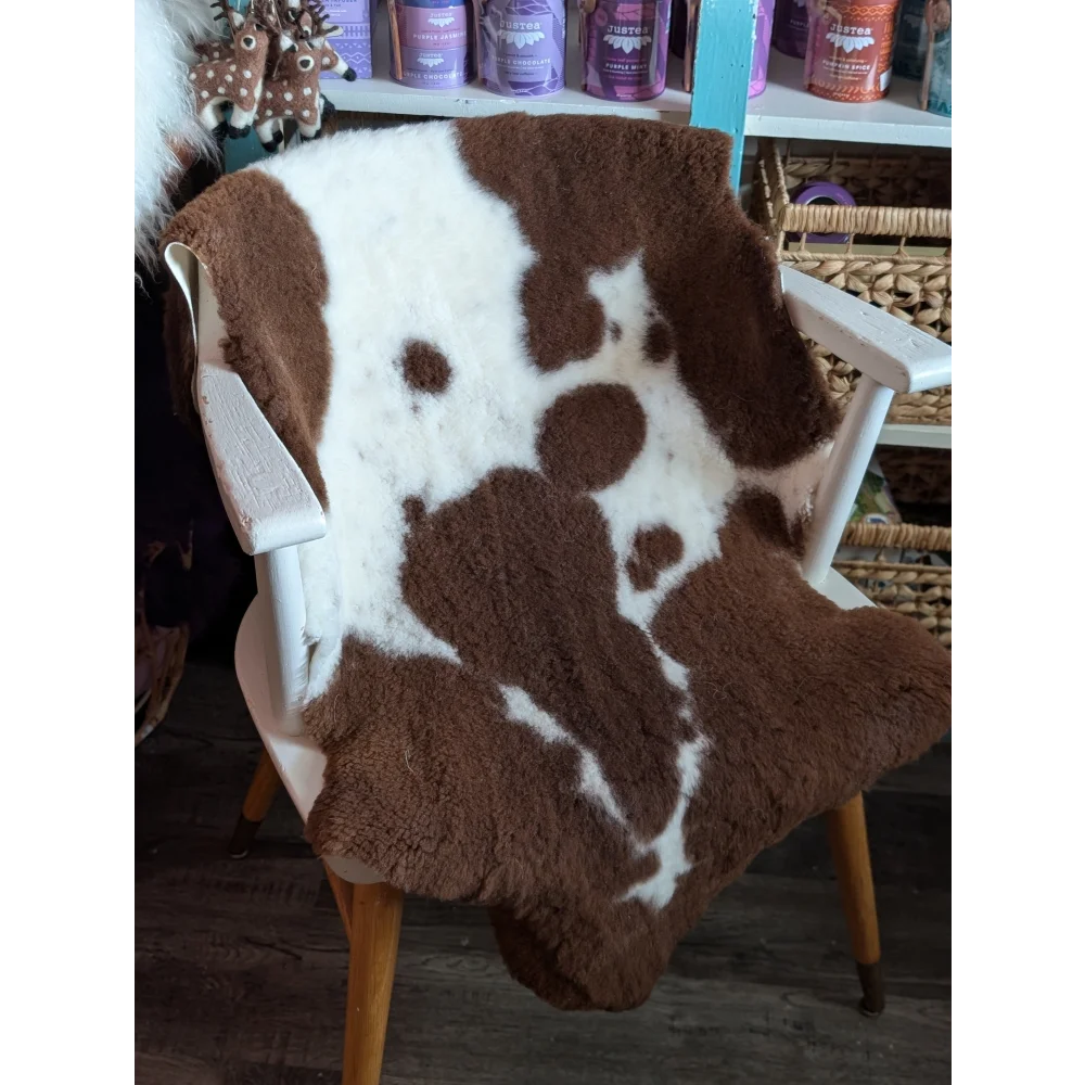 Brown and white highland spotted grade b sheepskin throw draped over chair perfect for cozy sheepskin rugs