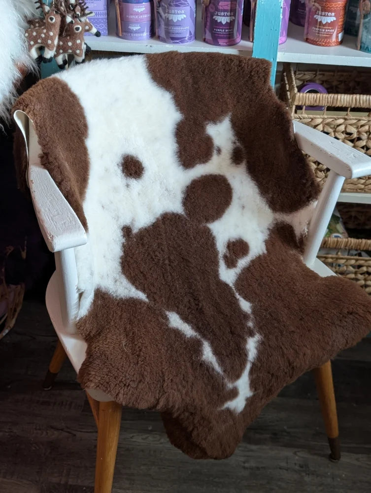 Brown and white highland spotted grade b sheepskin throw draped over chair perfect for cozy sheepskin rugs
