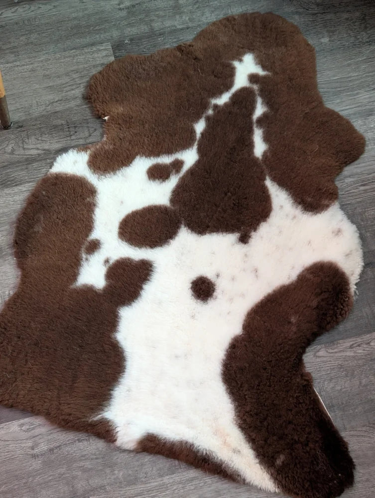 Brown and white highland spotted grade b sheepskin rug with plush fluffy texture perfect for cozy decor