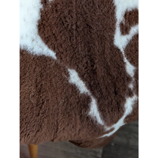 A plush brown and white highland spotted grade b sheepskin blanket with a soft fuzzy texture perfect for cozy use