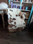 A plush white and brown tibet highland spotted grade a- sheepskin rug draped over a chair