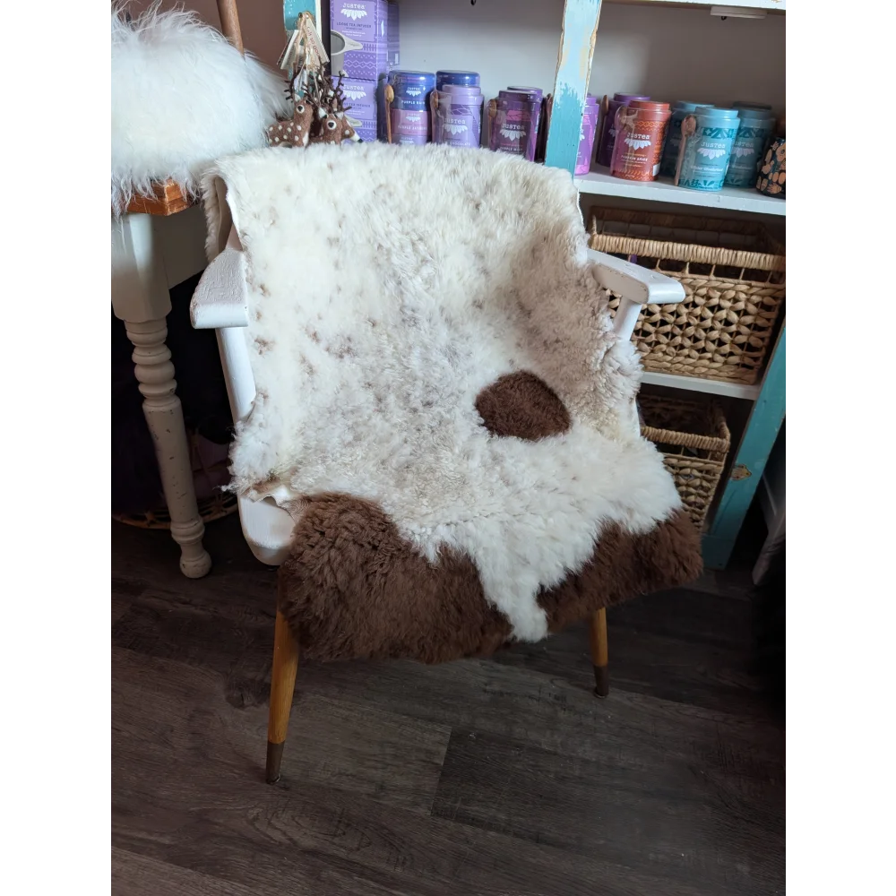 White and brown tibet highland spotted grade a- sheepskin chair cover draped over white wooden armchair with yellow legs