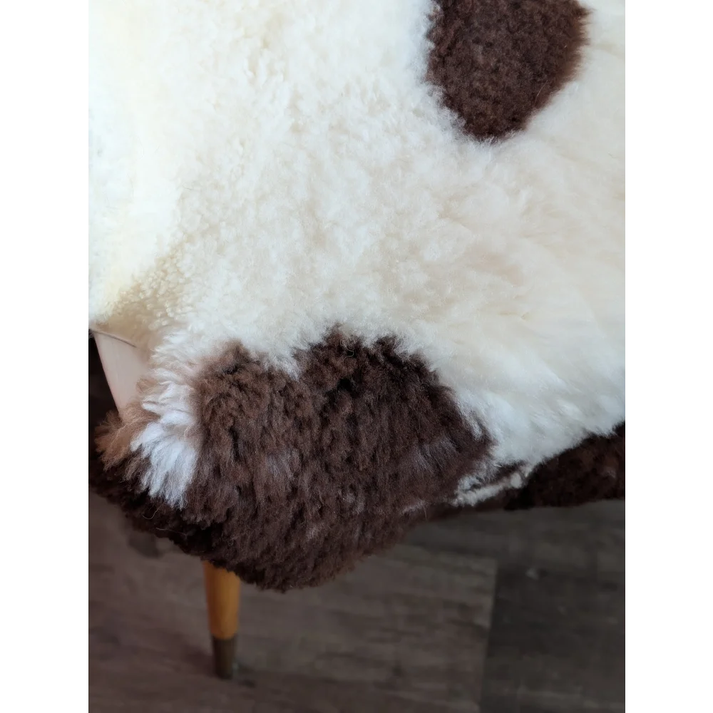 A soft tibet highland spotted grade a- sheepskin throw blanket in white and brown with a plush curly texture