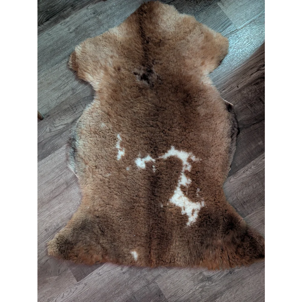A natural brown tibet highland spotted grade a- sheepskin rug with soft fluffy texture and subtle white markings