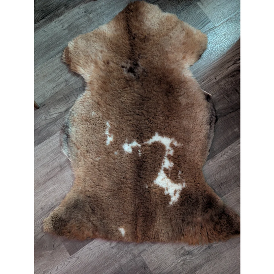 A natural brown tibet highland spotted grade a- sheepskin rug with soft fluffy texture and subtle white markings
